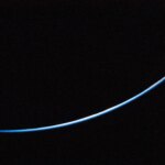 The edge of Earth is a thin line curving upward from left to right. The line is different shades of blue.