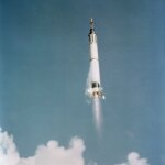 In this view from below, the Mercury-Redstone 3 space vehicle shines in the morning sun as it soars into the blue sky above Cape Canaveral, Florida.