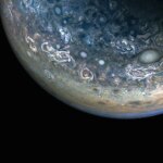 Three quarters of Jupiter can be seen in this photo; the darkness of space covers the bottom of the image. Green and blue swirls cover the planet's surface.