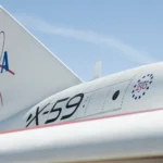 A close-up of NASA's X-59 tail showing a NASA graphic on the tail, X-59 on the side of the jet engine, and a Freedom 250 logo toward the front of the engine.